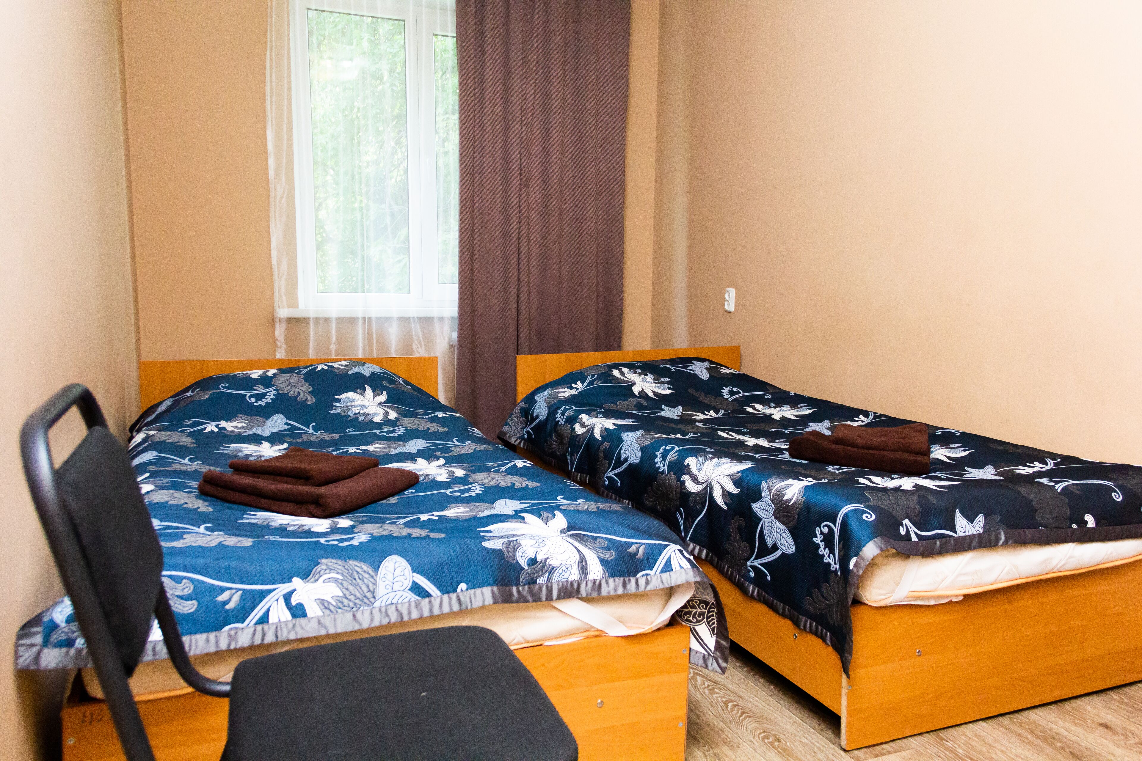 Two single beds with floral bedding, a wooden desk, and a chair.