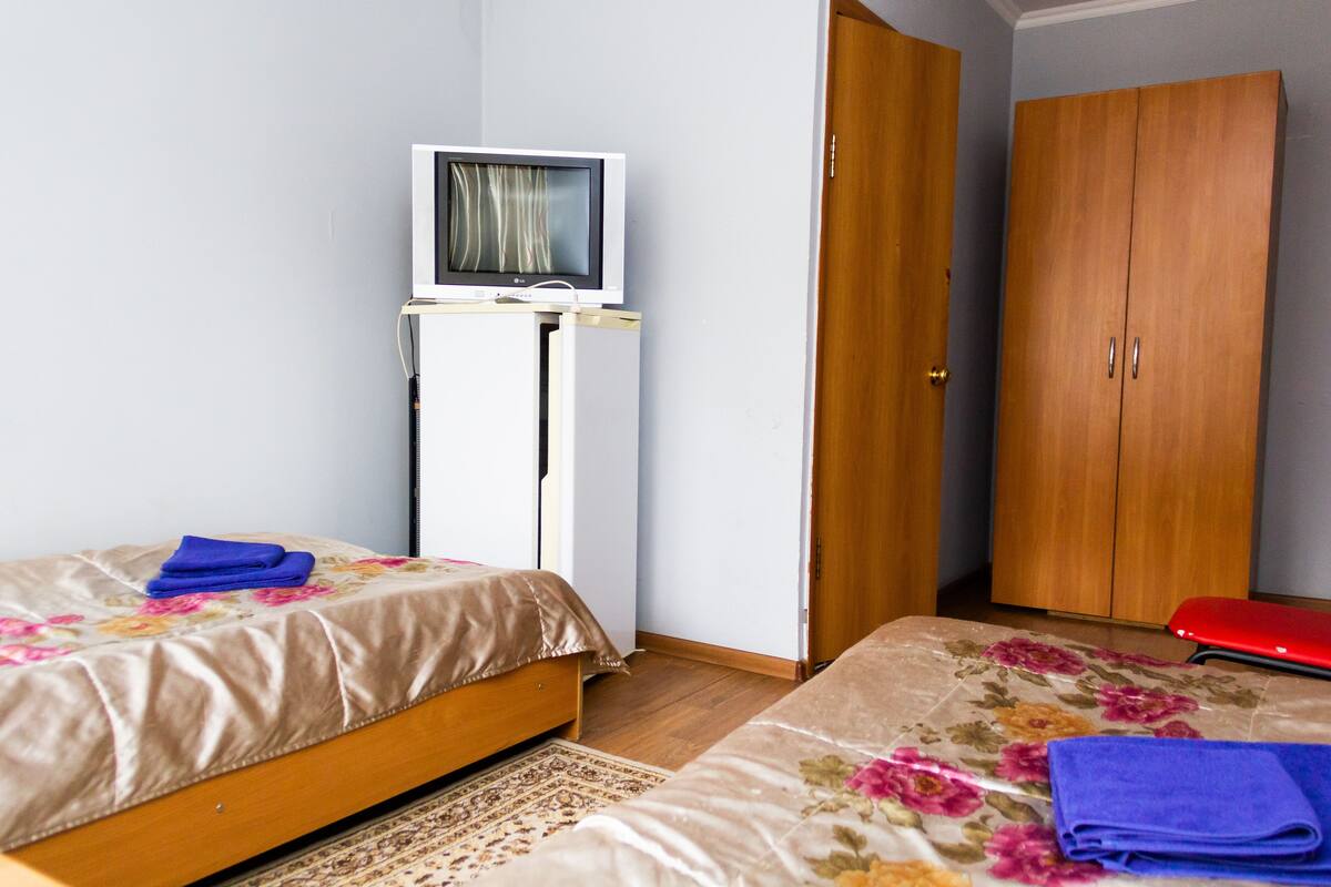 Un dormitorio con dos camas, un televisor sobre un mueble bajo y un armario.