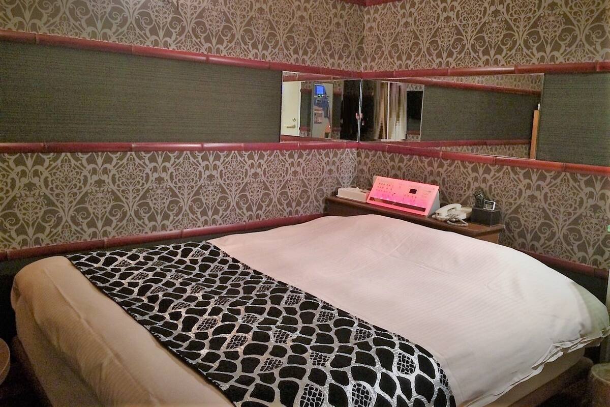 Ein Zimmer mit einem Bett, einem Schreibtisch mit Computer und einem Spiegel an der Wand.