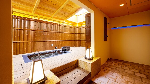 A wooden spa area with a hot tub, steps, and a bamboo wall.