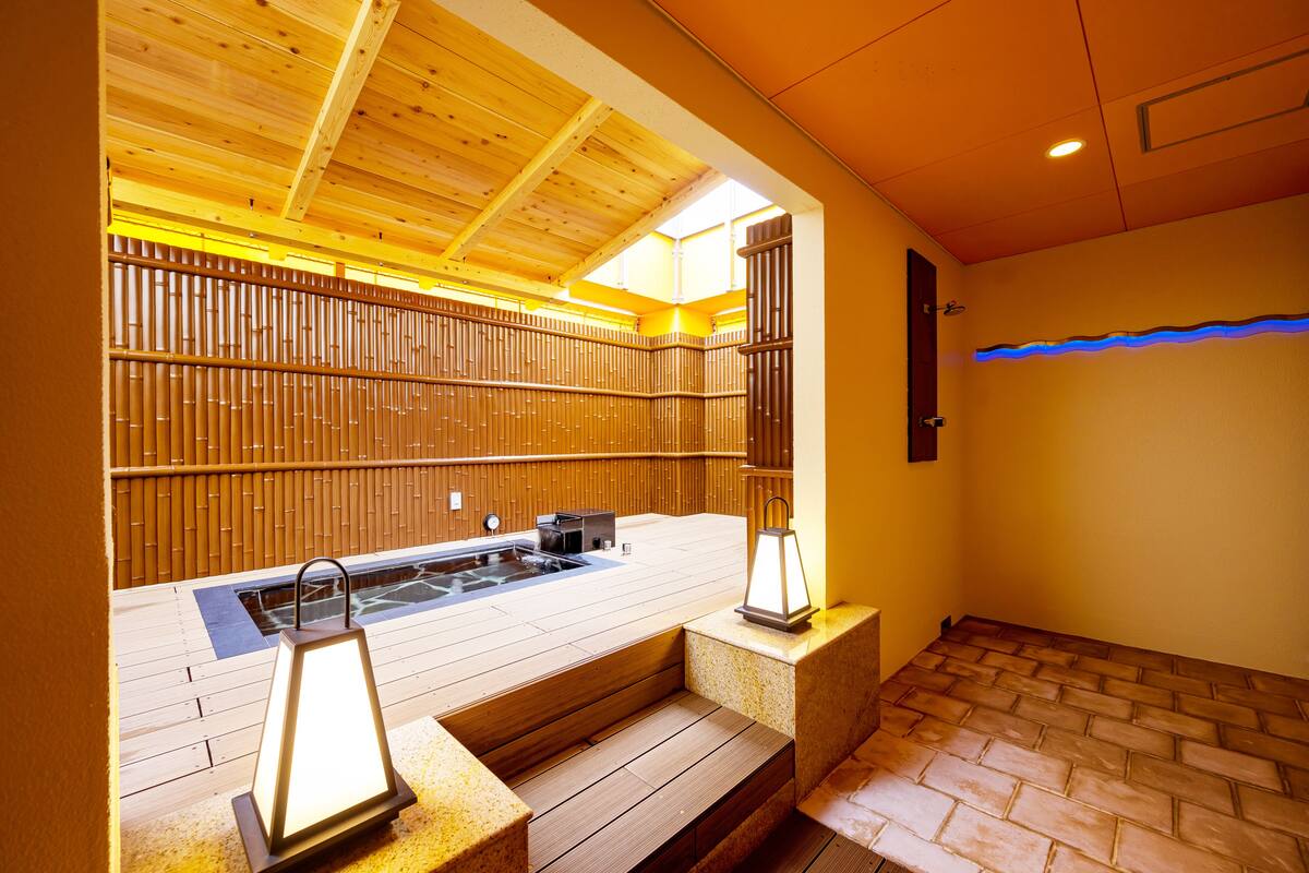 A wooden spa area with a hot tub, steps, and a bamboo wall.