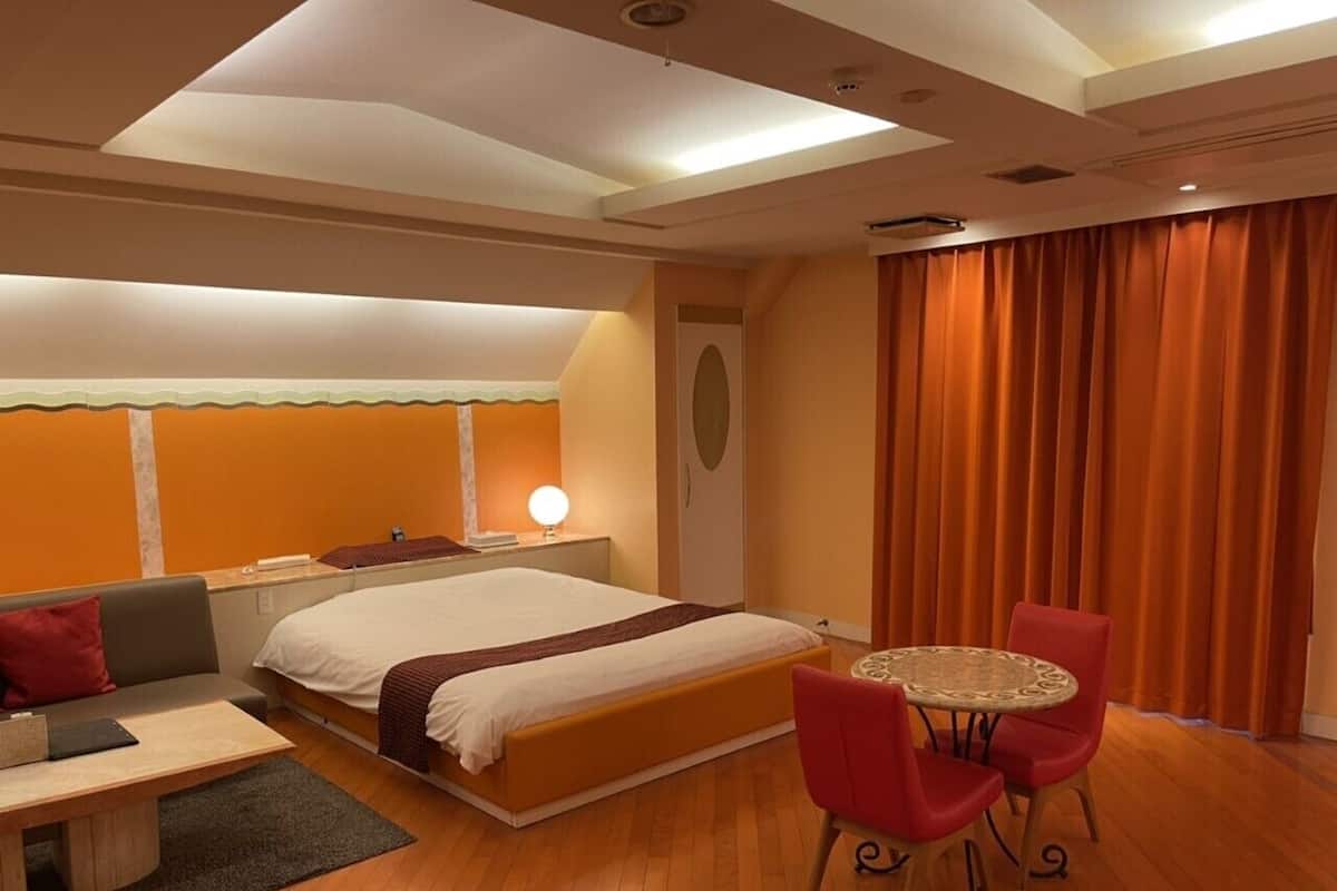 A hotel room with a bed, a desk, a chair, and a table.
