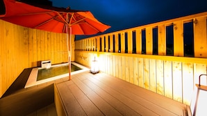 A wooden deck with a hot tub and an umbrella.