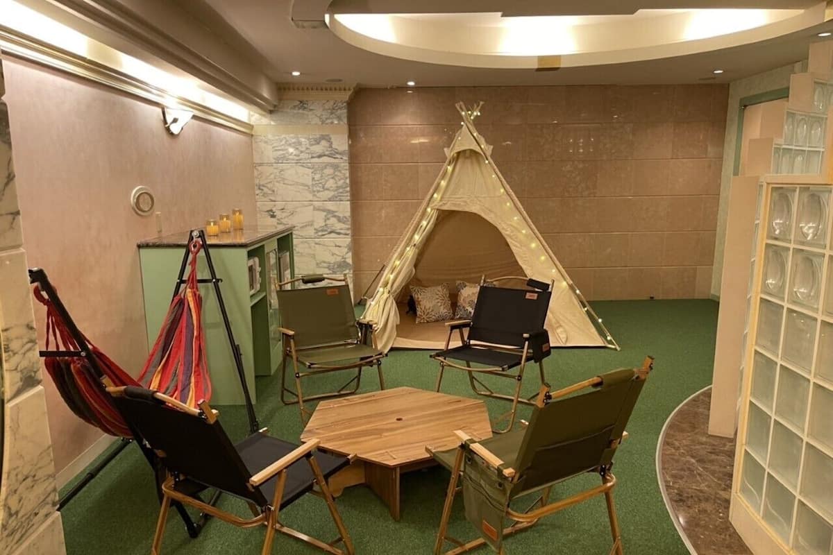 A cozy room with a round table, four chairs, a hammock, and a teepee.