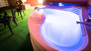 A hot tub with a lighted edge, surrounded by a green carpet and dark metal furniture.