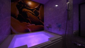 A modern bathroom with a large bathtub, a shower, and a wall mural. - Hotel New York - Adults Only (Yokohama)