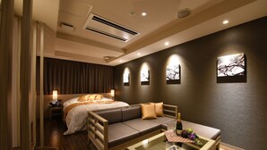 A modern hotel room with a bed, a sofa, a glass coffee table, and wall-mounted artwork. - Hotel New York - Adults Only (Yokohama)