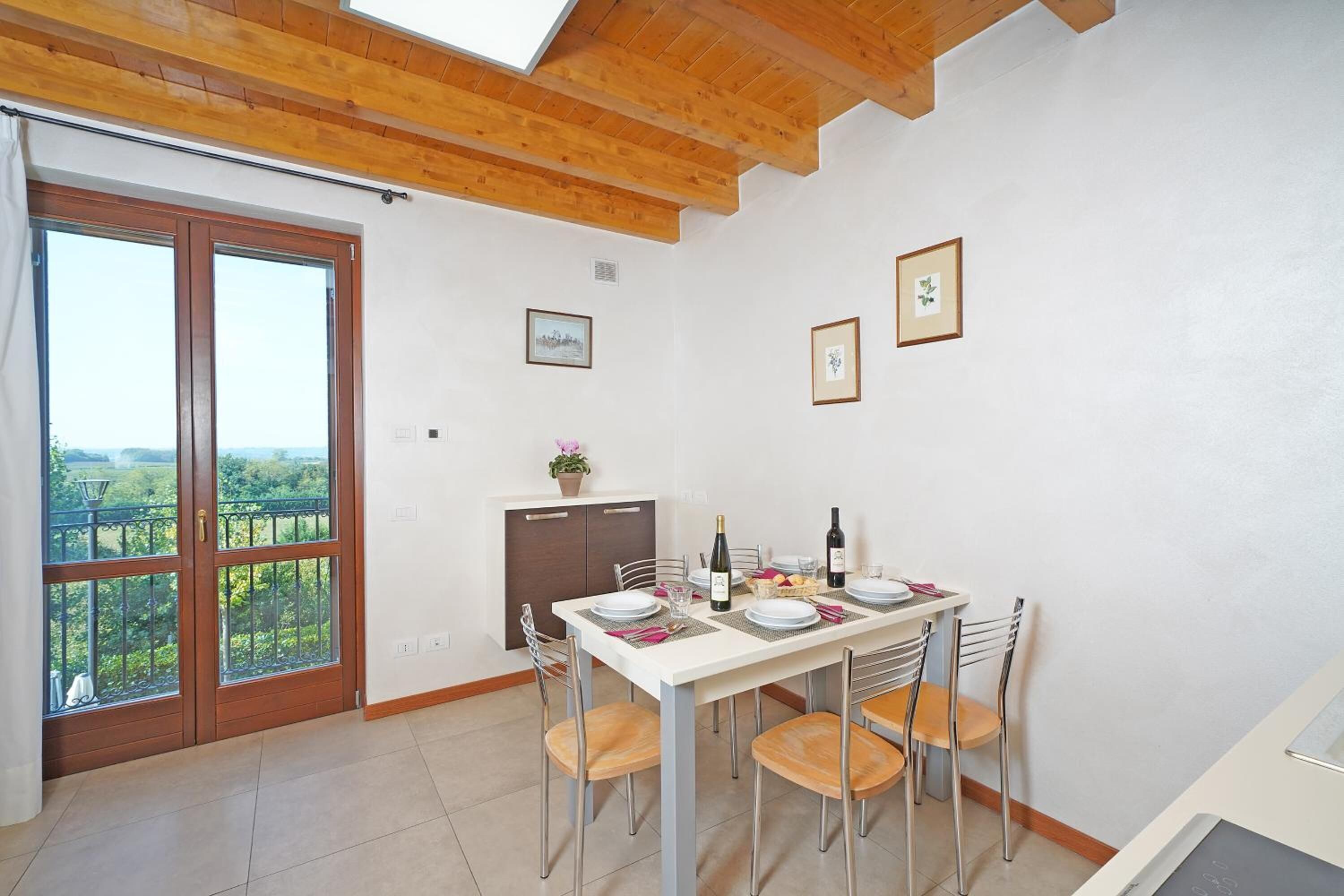 Un comedor con una mesa dispuesta para cuatro, vista a través de un ventanal y techo de madera.