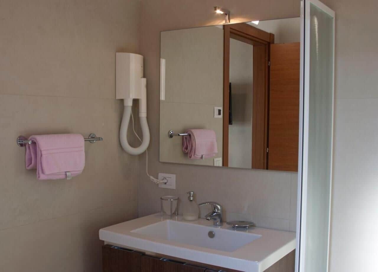 A bathroom with a white sink, a mirror, a towel rack, and a wall-mounted phone.