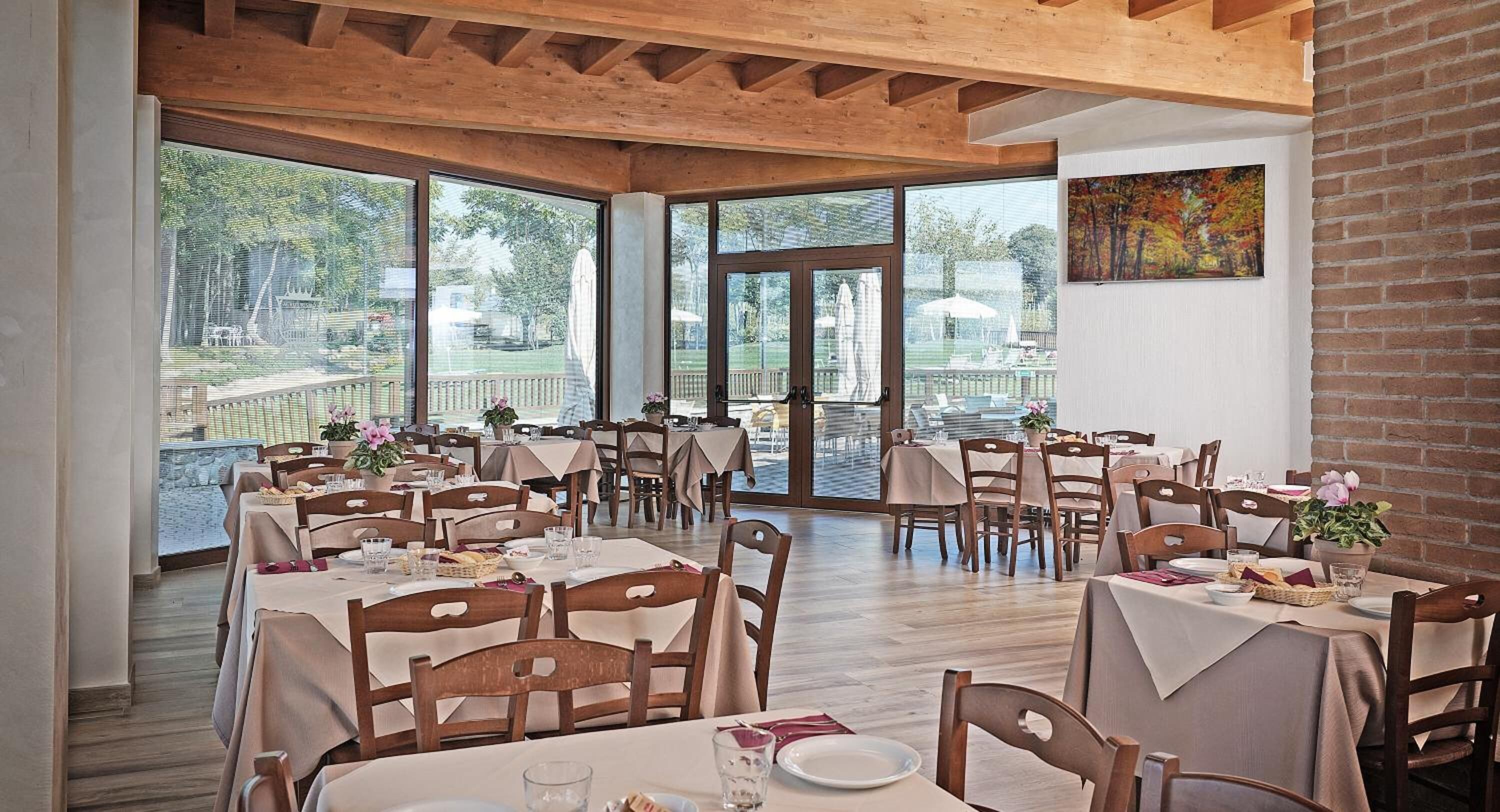 A restaurant with multiple tables and chairs, large windows, and a view of the outdoors.