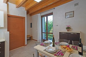 Uma área de refeições com uma mesa posta para dois, uma garrafa de vinho e uma cesta de pão.