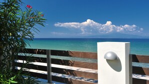 A coastal view with a wooden bench and a white wall with a light fixture.