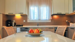 A modern kitchen with white cabinets, a stainless steel sink, and a bowl of fruit on the counter.