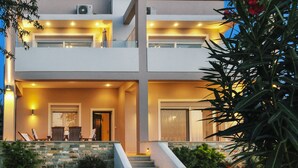 A modern two-story house with a stone staircase leading to the entrance, a balcony with outdoor seating, and a well-lit front porch.