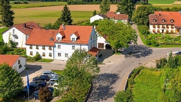A rural village with traditional buildings, a main road, and parked cars. - Gästehaus Neubauer (Althegnenberg)