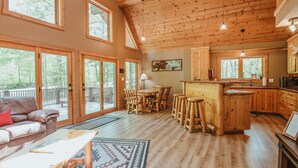 Un salón amplio con techo de madera, ventanas grandes y una acogedora disposición de asientos.