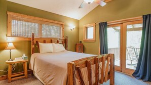 Un dormitorio con cama, cabecero de madera, mesita de noche con lámpara y ventana con cortinas.