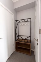 Habitación de esquina con armario empotrado, un banco de madera y perchero.