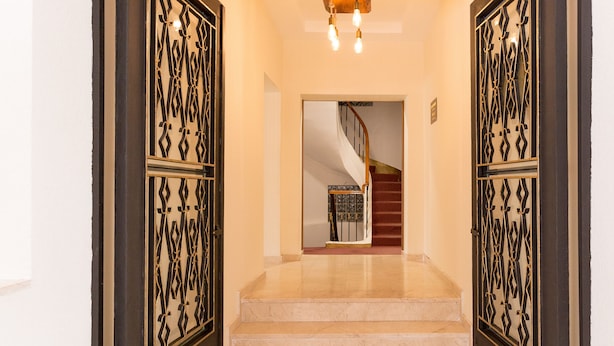 A hallway with a marble floor leading to a staircase with a wooden handrail. - Baskent Konukevi (Ankara)