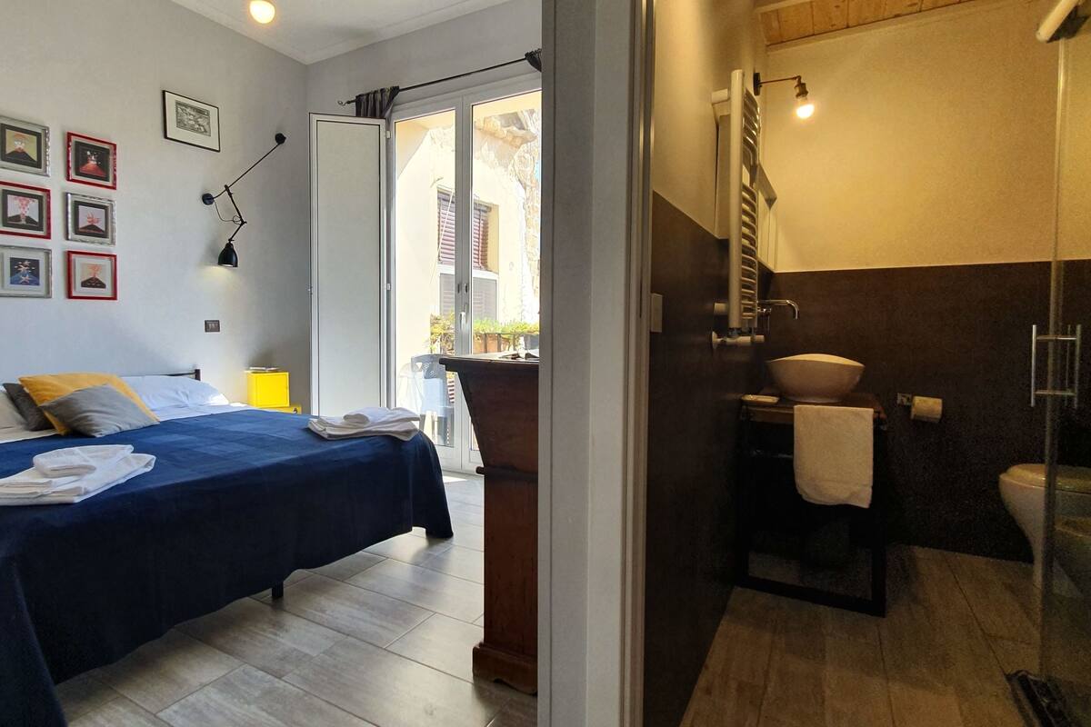 A bedroom with a bed, bedside tables, and a bathroom with a shower and toilet.