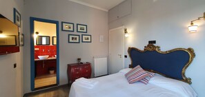 Ett sovrum med en stor säng, en röd byrå, en spegel och inramade tavlor på väggen.