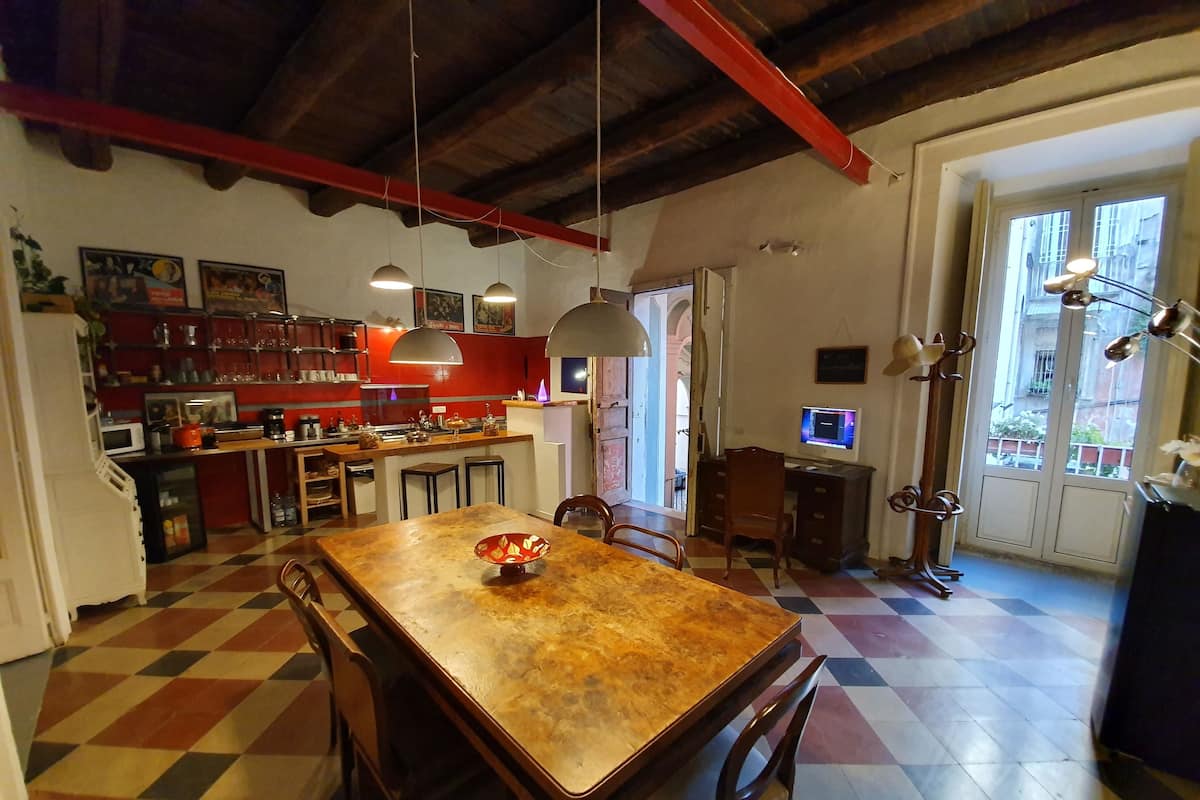 A kitchen with a checkered floor, a dining table with chairs, a TV, and a computer desk.