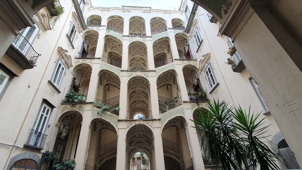 Un edificio de varios pisos con balcones, ventanas de arco y molduras decorativas.
