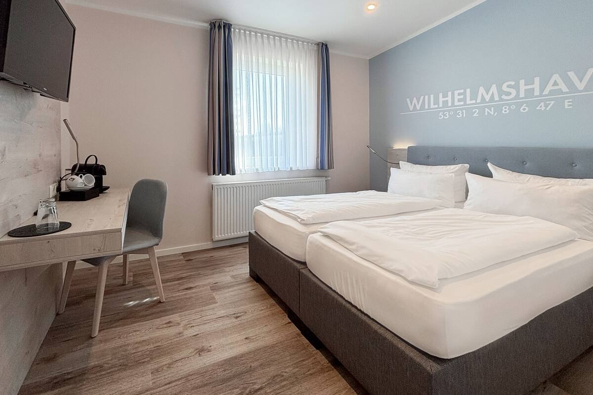 Ein Hotelzimmer mit Bett, Schreibtisch, Stuhl und Fernseher.