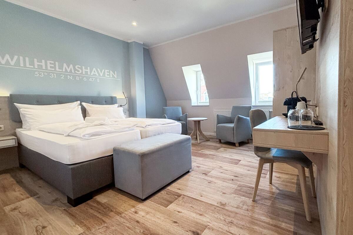 Ein modernes Hotelzimmer mit einem großen Bett, einem Schreibtisch und einem Stuhl.