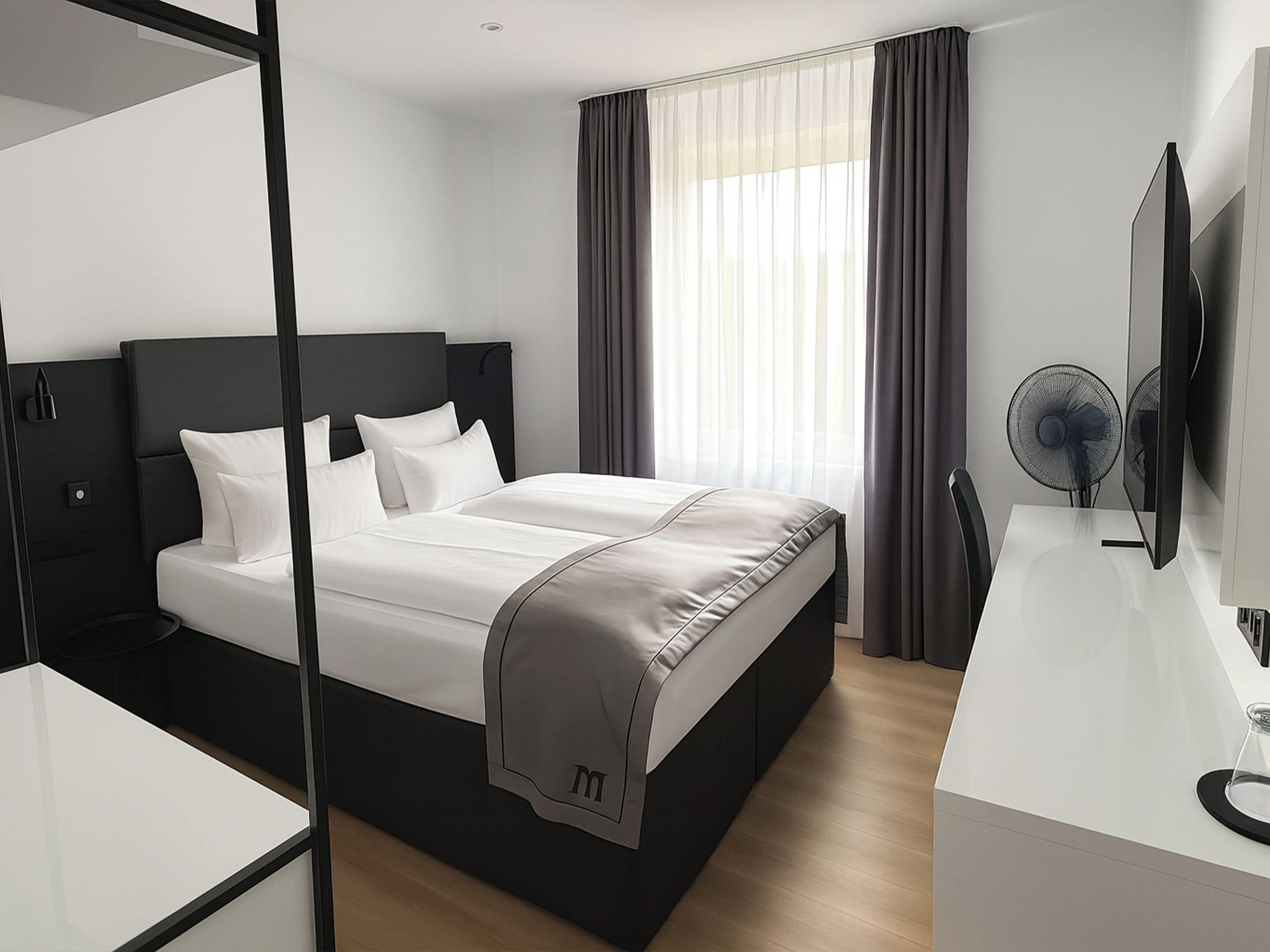 A modern hotel room with a large bed, a desk, a flat-screen TV, and a window with curtains.