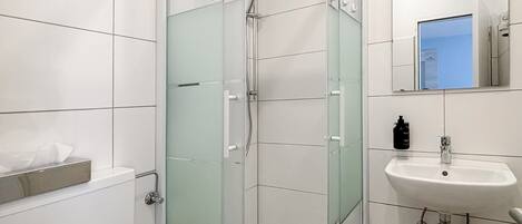 A modern bathroom with a glass-enclosed shower, a white sink, and a toilet.