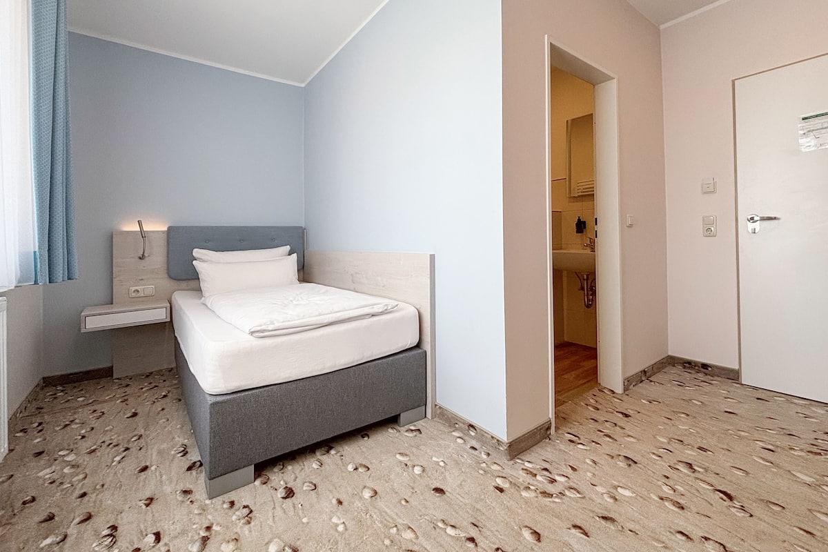 Ein Schlafzimmer mit Bett, Nachttischen und einer Tür zu einem Badezimmer.