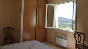 A bedroom with a bed, a window with a view of the outdoors, a radiator, and a wooden wardrobe. - PROHE MIREPOIX EXCEPTIONAL VIEW OF PYRENEES (Tréziers)