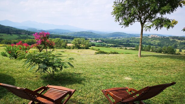 Two wooden lounge chairs facing a grassy field with a tree and a distant castle. - PROHE MIREPOIX EXCEPTIONAL VIEW OF PYRENEES (Tréziers)