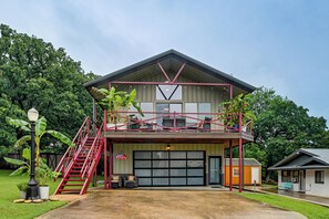 Ein zweistöckiges Gebäude mit Garage, einem Balkon mit roten Geländern und einer Treppe, die zum oberen Stock führt.