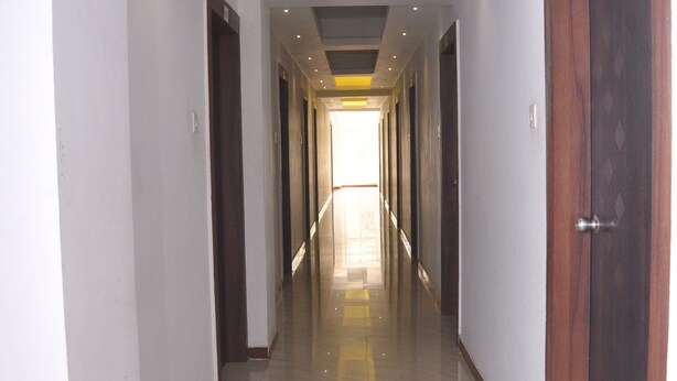 A long, narrow hallway with a polished floor and a series of doors on one side. - Sai Arya Lodging & Hall (Mangaluru)