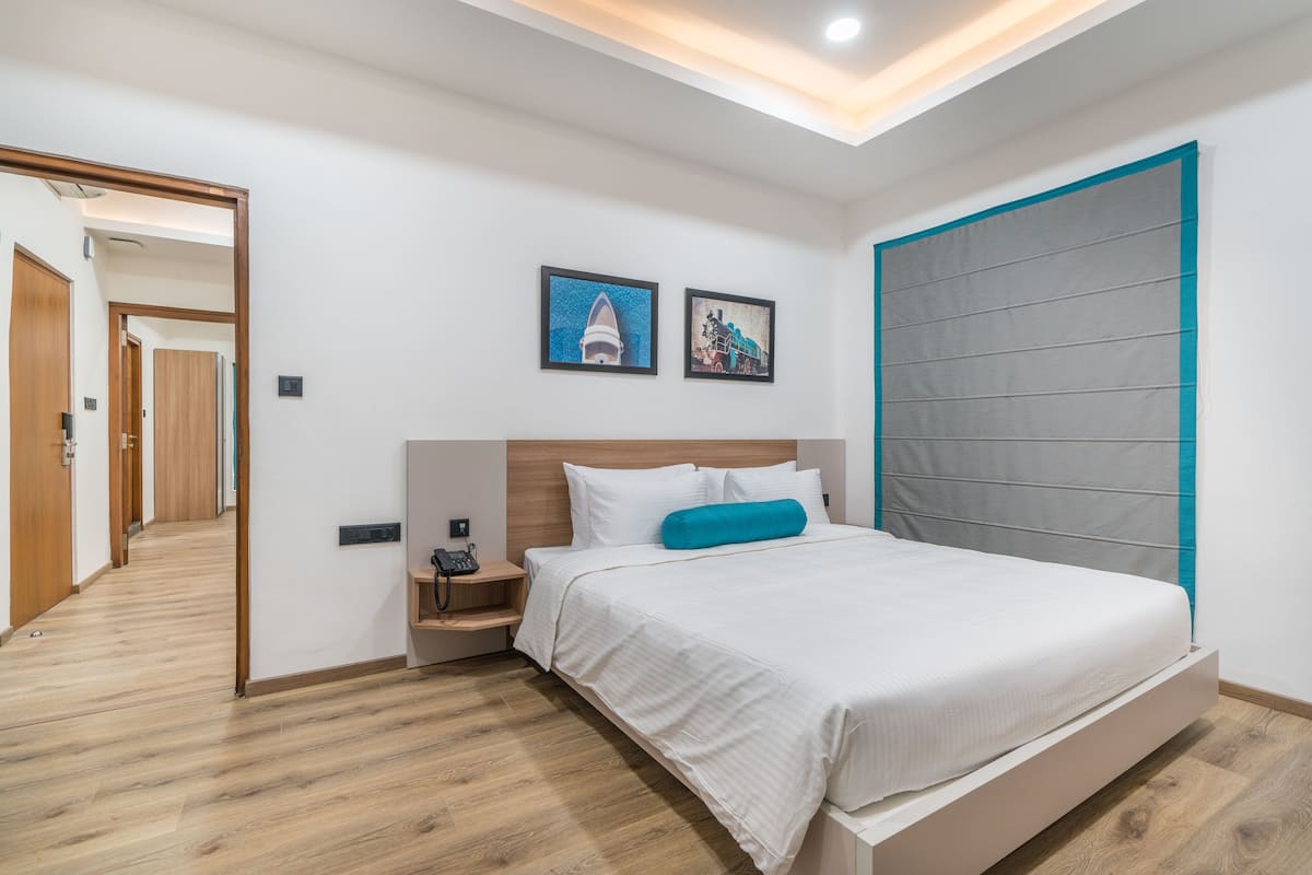 Quarto moderno com cama, mesa de cabeceira e uma janela grande.
