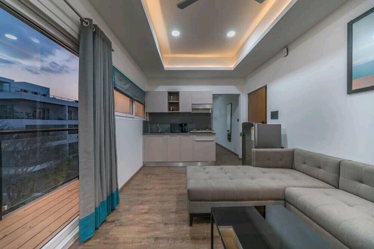 Uma sala de estar moderna com sofá seccional, mesa de centro e vista para o horizonte urbano através de grandes janelas.