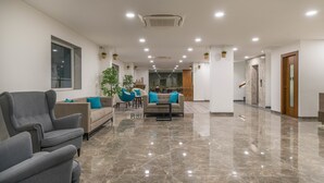 Un vestíbulo amplio con piso de mármol pulido, un conjunto de sofás y un comedor.