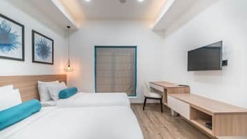Une chambre d’hôtel moderne équipée de deux lits, d’un bureau, d’une chaise, d’une télévision et d’une fenêtre avec des stores.