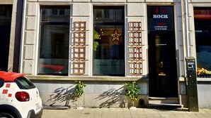 Un bâtiment avec une porte noire sur laquelle on peut lire le mot « ROCK » et une petite plante devant.