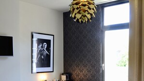 Une chambre d’hôtel moderne avec un grand lit, un bureau, une chaise, un tableau encadré au mur et une fenêtre avec des rideaux.