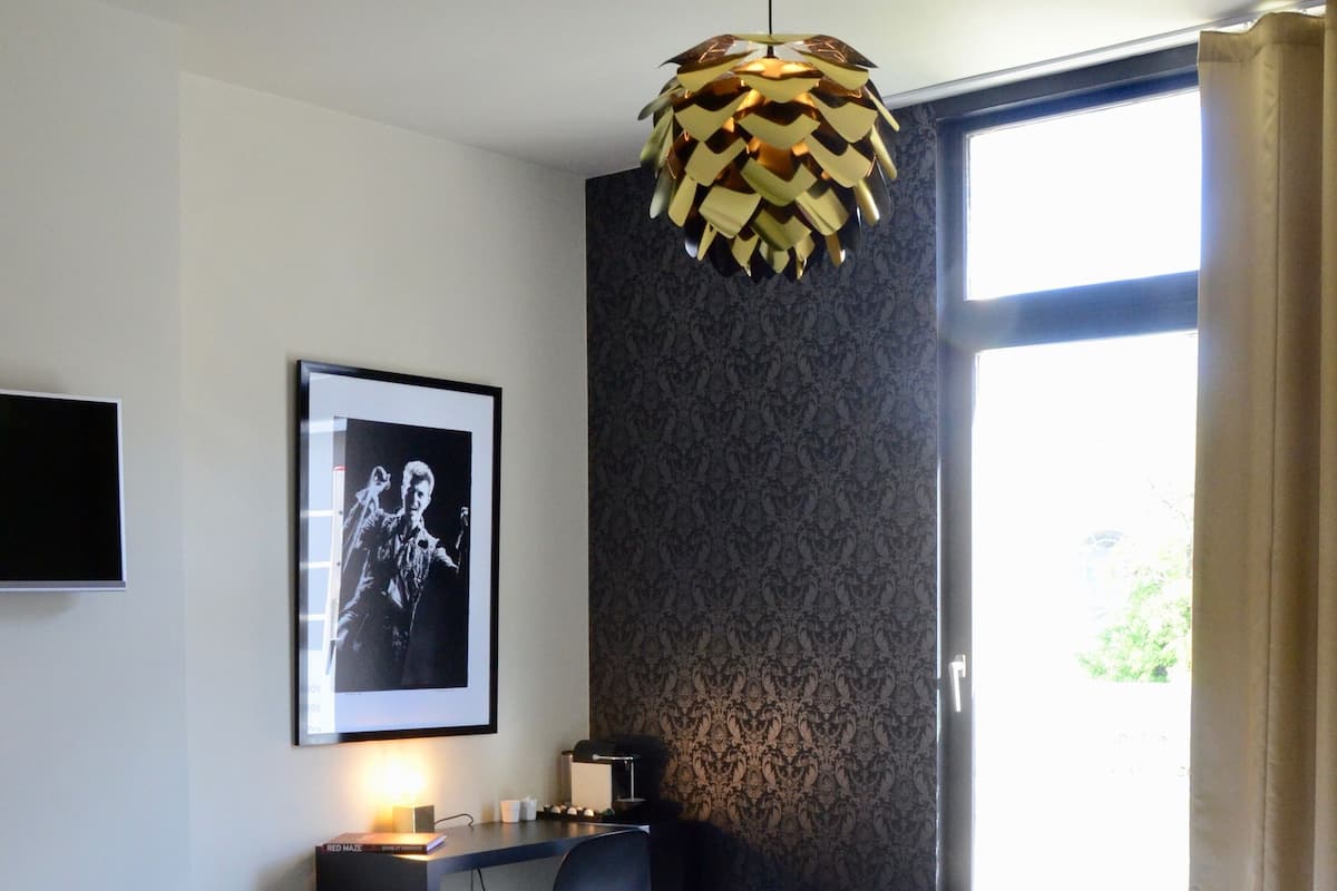 Een moderne hotelkamer met een groot bed, een bureau, een stoel, een lijst met een afbeelding aan de muur en een raam met gordijnen.