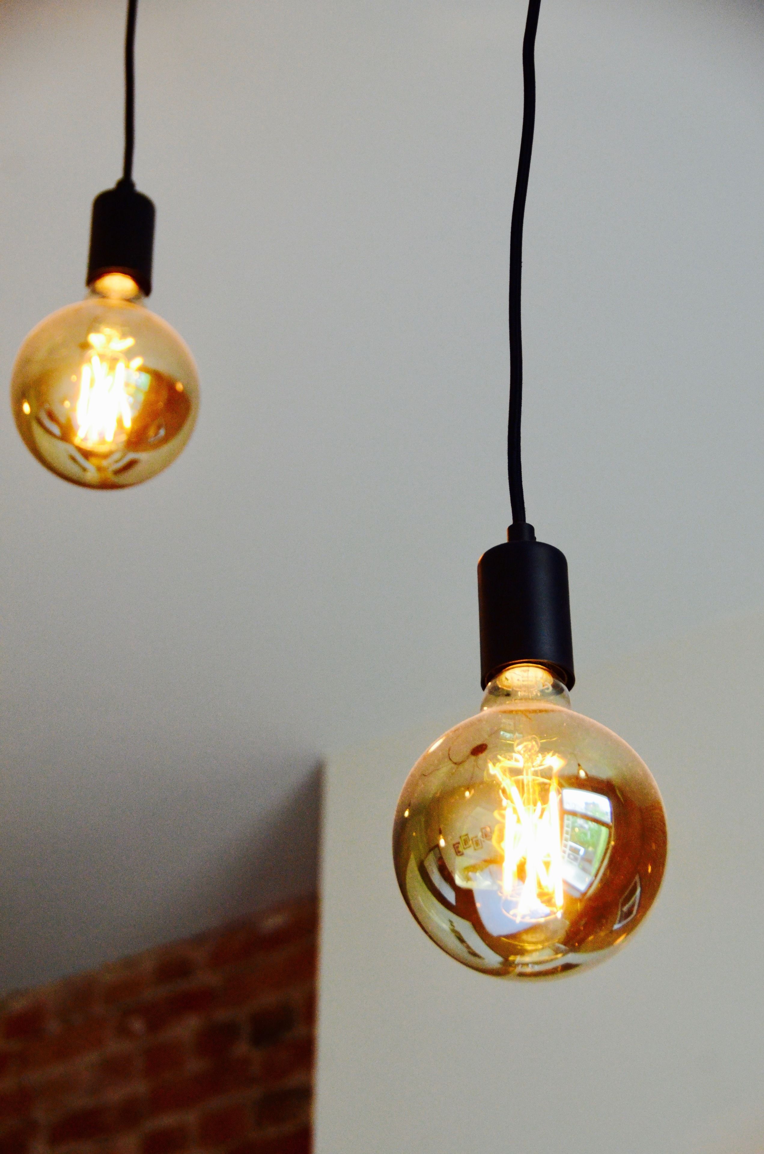 Two hanging spherical light bulbs with visible filaments, connected by black cords.