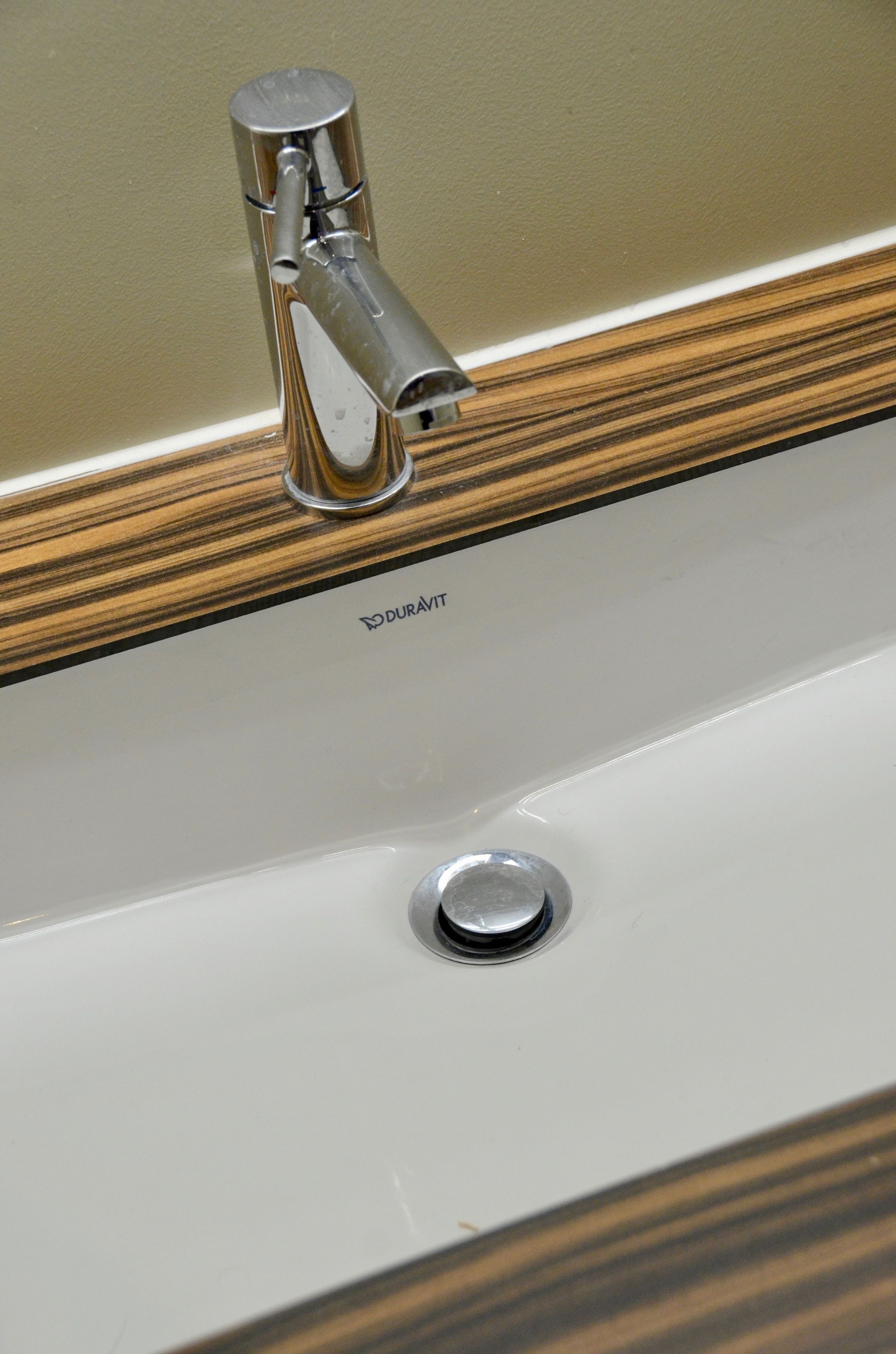 Un lavamanos de baño con una grifería moderna y un mueble de tocador de madera.
