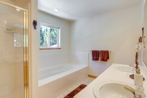Un baño con bañera, dos lavamanos y una ventana.