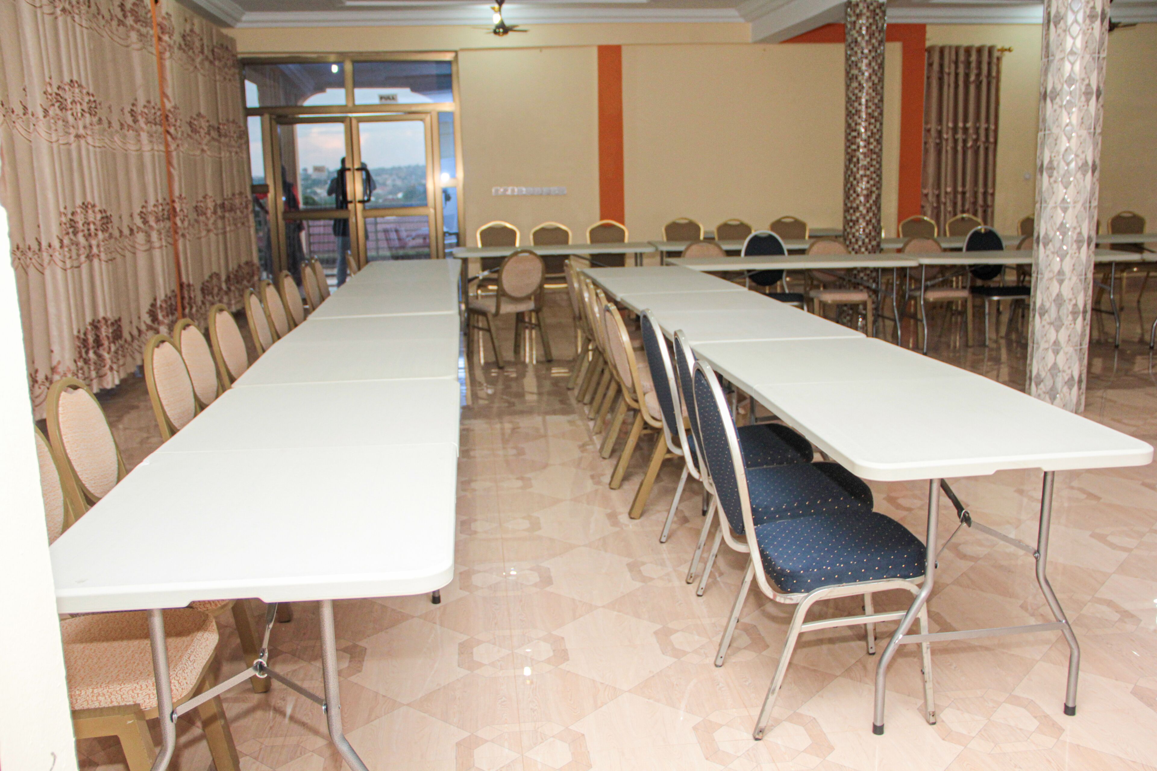 A conference room with long tables and chairs, a view through the door, and a patterned floor.