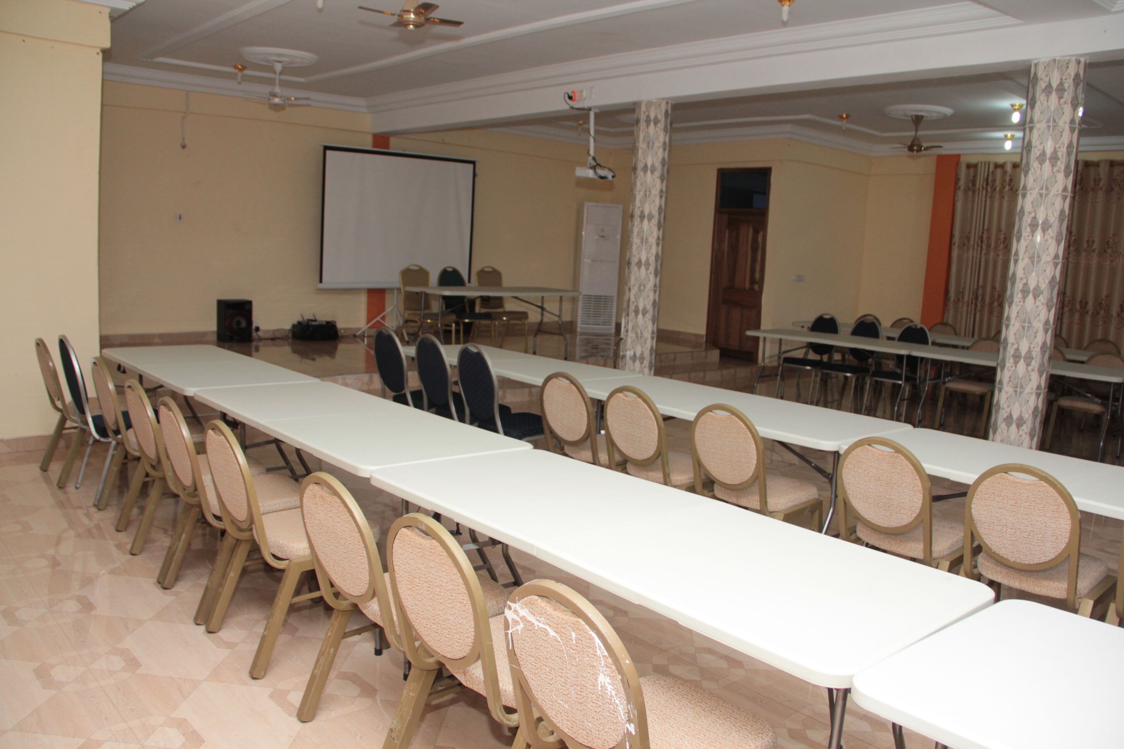 Ein Konferenzraum mit langem Tisch, mehreren Stühlen, einer Tafel und einer Projektionsleinwand.