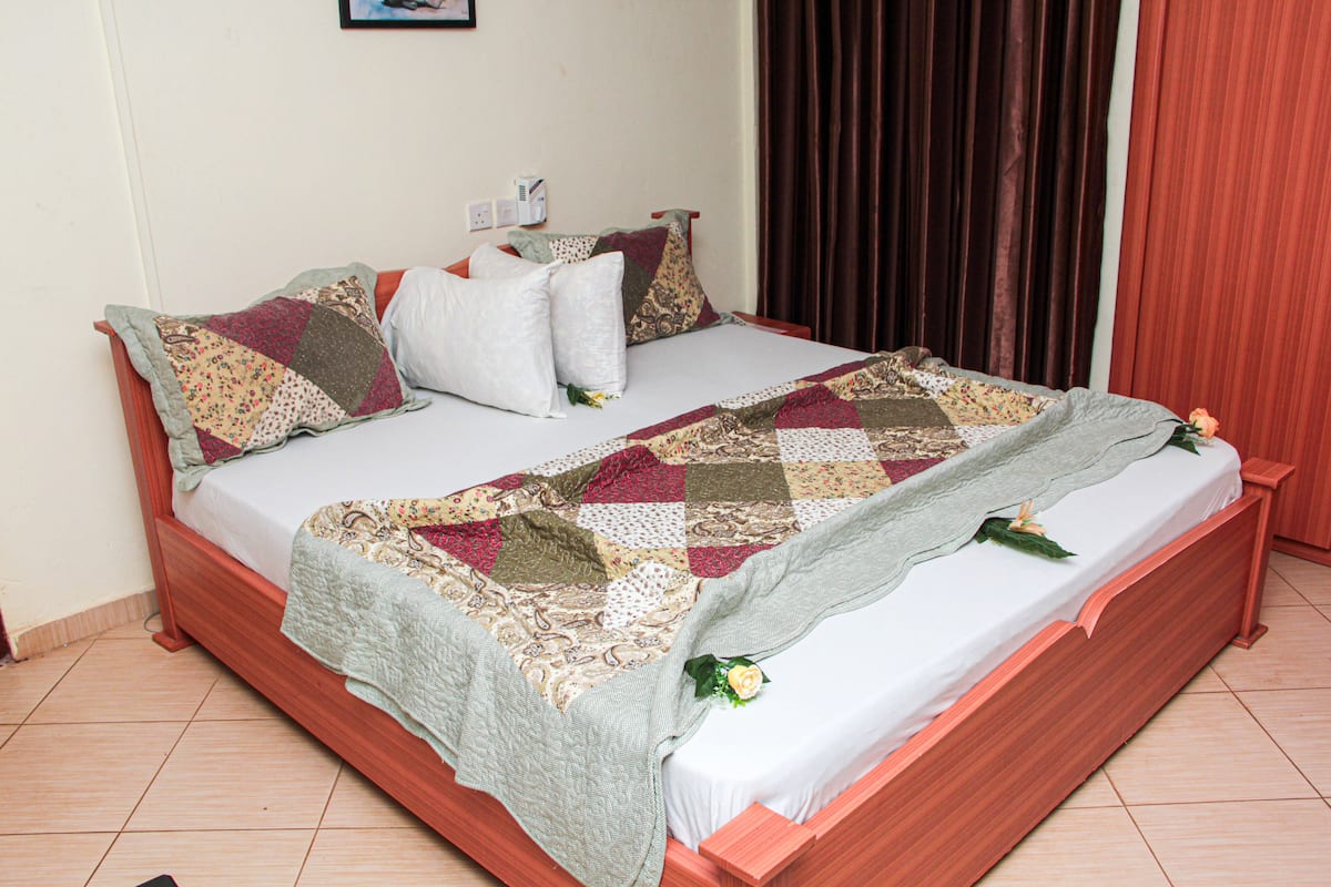 A neatly made bed with a quilt and pillows, a wooden headboard, and a small bedside table.