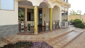 Un espace d’accueil avec un hall d’entrée carrelé, une enseigne indiquant « RÉCEPTION », et une porte vitrée donnant accès à l’intérieur.